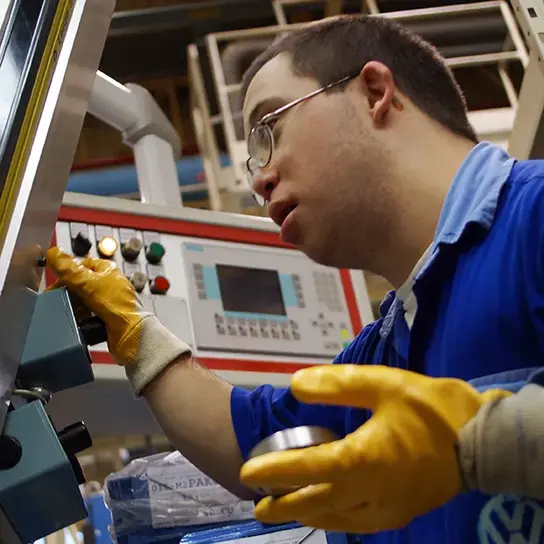 Ein Mann mit Behinderung bedient eine Maschine in einer Volkswagen-Fabrik in Argentinien.