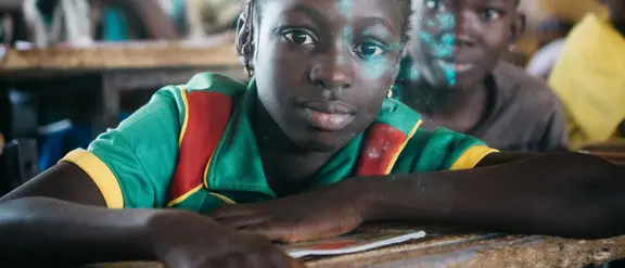 Ein aufmerksames Mädchen sitzt in einem Klassenzimmer in  Burkina Faso. Die Szene zeigt die Bedeutung von Bildung und die Hoffnung auf eine bessere Zukunft durch Lernen.