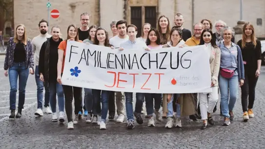 Das Bild zeigt Terre des Hommes-Aktivist*innen bei einer Demo mit einem Banner "Familiennachzug - jetzt!"