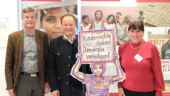 Das Bild zeigt Christoph Dallmayr, stv. Vorsitzender Präsidium Terre des Hommes; Landrat Robert Niedergesäß; Silvia Rogg, ehrenamtliche Mitarbeiterin Terre des Hommes vor den Ausstellungsbannern